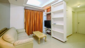 A living room with a sofa, a coffee table, a TV, and a bookshelf.