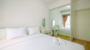 A hotel room with a large bed, a bedside table with a mirror, a dresser, and a walk-in closet.