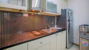 A kitchen with a tiled backsplash, stainless steel appliances, and white cabinetry.