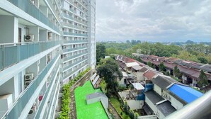 A high-rise building with multiple balconies, a rooftop pool, and a green space in the foreground. - Stylish & Comfy Studio at Dago Suites Apartment (Bandung)