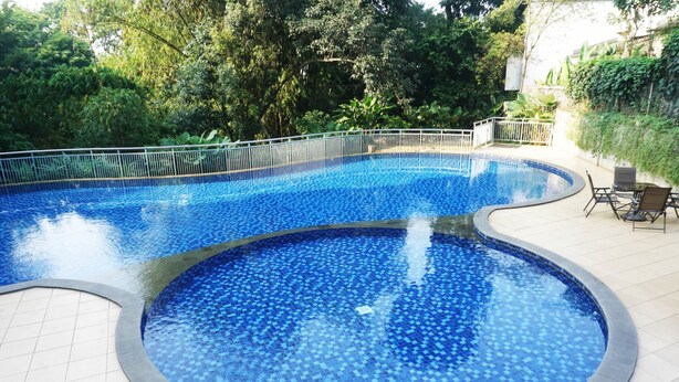 A swimming pool with a tiled edge and a surrounding fence. - Stylish & Comfy Studio at Dago Suites Apartment (Bandung)