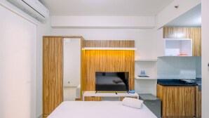 Une chambre d’hôtel équipée d’un lit, d’une télévision, d’une petite kitchenette et d’une armoire en bois.