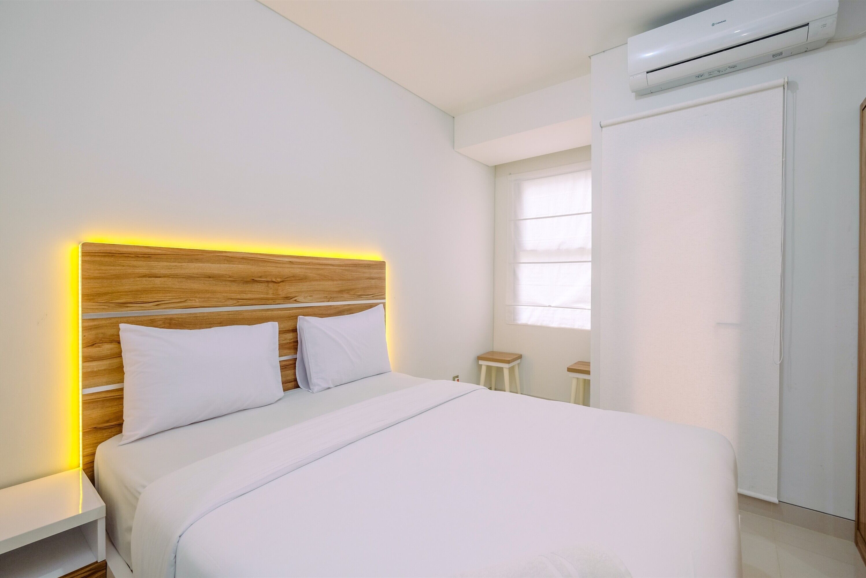 Un dormitorio moderno con cabecera de madera, ropa de cama blanca y una mesita de noche.