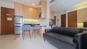 Una cocina moderna con armarios de madera, horno empotrado y una zona de comedor con dos sillas.