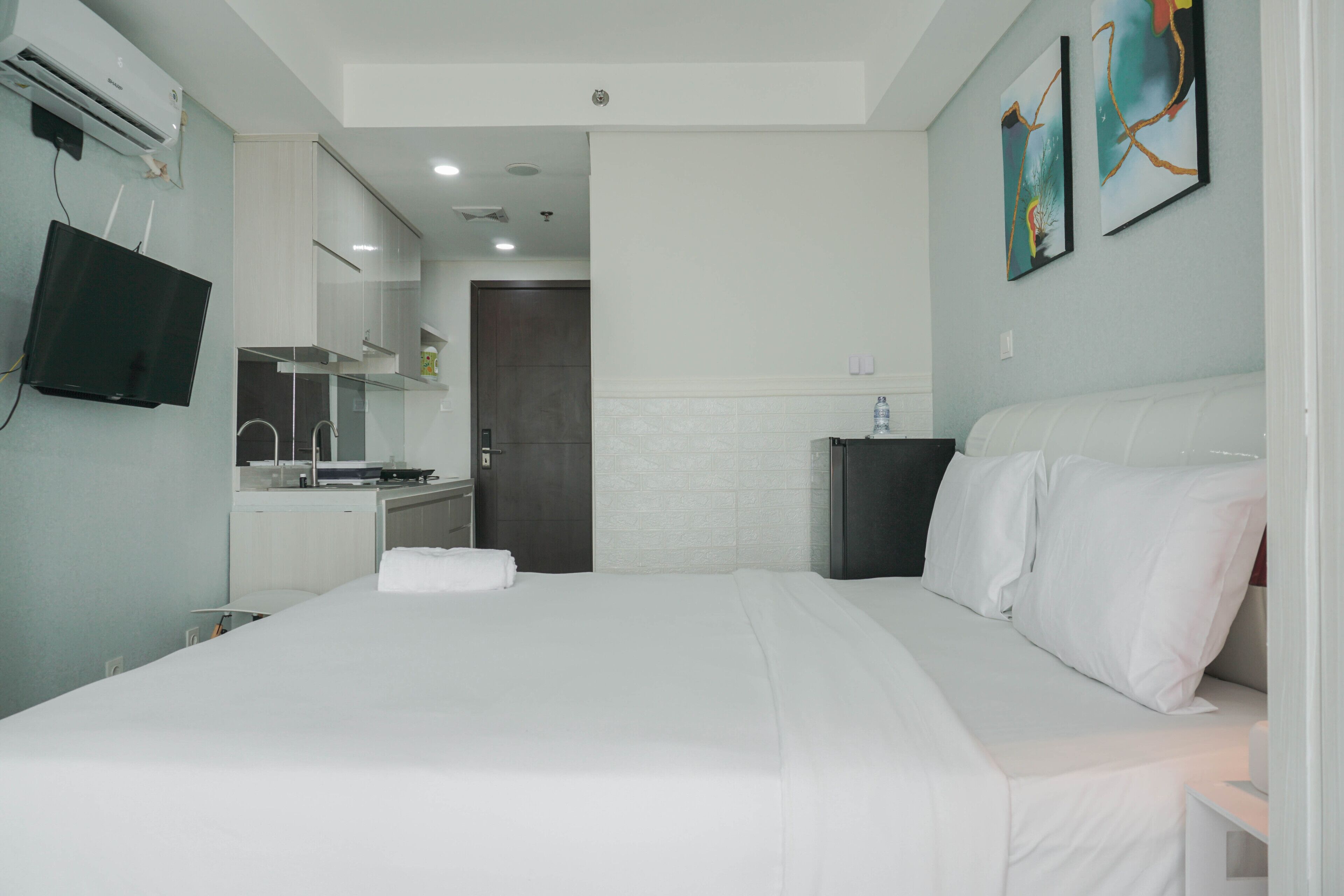 A hotel room with a bed, a TV, a small table, and a wall-mounted TV.