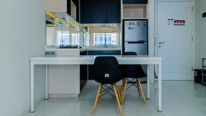 A modern kitchen with a white countertop, black chairs, and a white refrigerator.
