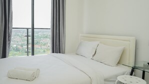 Habitación de hotel con una cama grande, una mesita de vidrio y vistas a un paisaje urbano a través de amplios ventanales.
