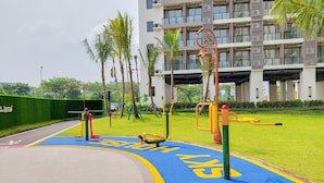 Un parque infantil con equipo de ejercicio y un carril bici azul.