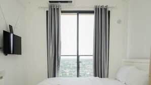 Una habitación de hotel moderna con una cama grande, un televisor de pantalla plana en la pared y vistas a la ciudad desde la ventana.