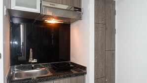 Uma cozinha compacta com fogão embutido, pia e coifa moderna.
