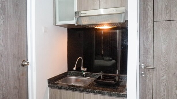 Cozinha compacta com pia de aço inoxidável, coifa moderna e armários de madeira.