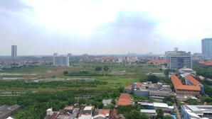 A cityscape with a mix of residential and commercial buildings, including a prominent tower and several multi-story structures. - Chic and Cozy Studio Apartment at Taman Melati Surabaya (Surabaya)