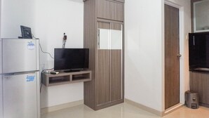 A compact room with a built-in TV on a shelf, a wardrobe, and a door. - Chic and Cozy Studio Apartment at Taman Melati Surabaya (Surabaya)