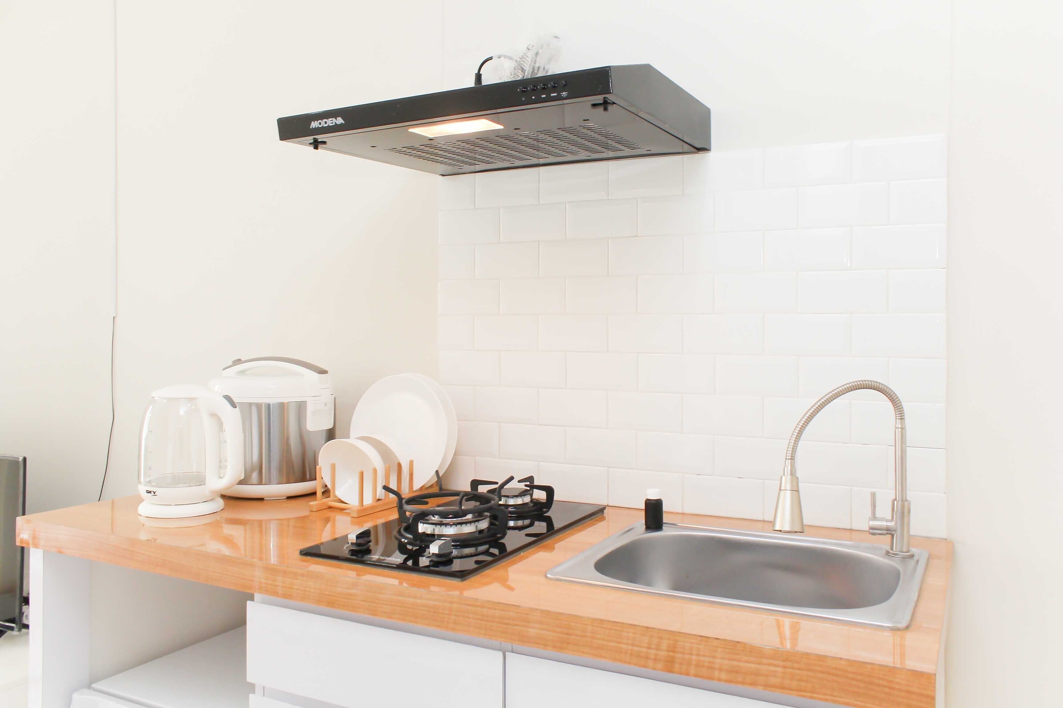 A modern kitchen with a stainless steel sink, a gas stove, a coffee maker, and a kettle.