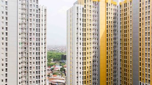Un edificio residencial de gran altura con varios pisos, balcones y vistas a un paisaje urbano de fondo.