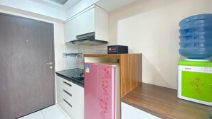 A compact kitchen with a refrigerator, a water dispenser, and a microwave. - Roomy 2BR Apartment at Jarrdin Cihampelas Apartment (Bandung)