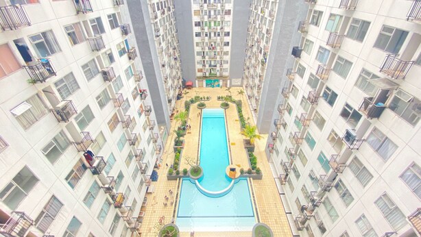 A high-rise residential building with a central swimming pool surrounded by balconies and terraces. - Roomy 2BR Apartment at Jarrdin Cihampelas Apartment (Bandung)