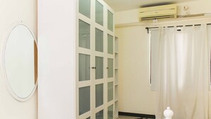 A bathroom with a white vanity, a large mirror, a frosted glass cabinet, a shower curtain, and a tiled floor. - White and Nice 1BR at Bassura City Apartment (Jakarta)