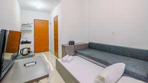 Ein kleines Hotelzimmer mit einem Bett, einem Schlafsofa, einem Schreibtisch mit Wasserkocher und einem Fernseher.