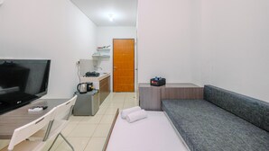 Ein kleiner, sauberer Raum mit einem Bett, einer Schlafcouch, einem Fernseher, einem Schreibtisch und einer Küchenzeile.