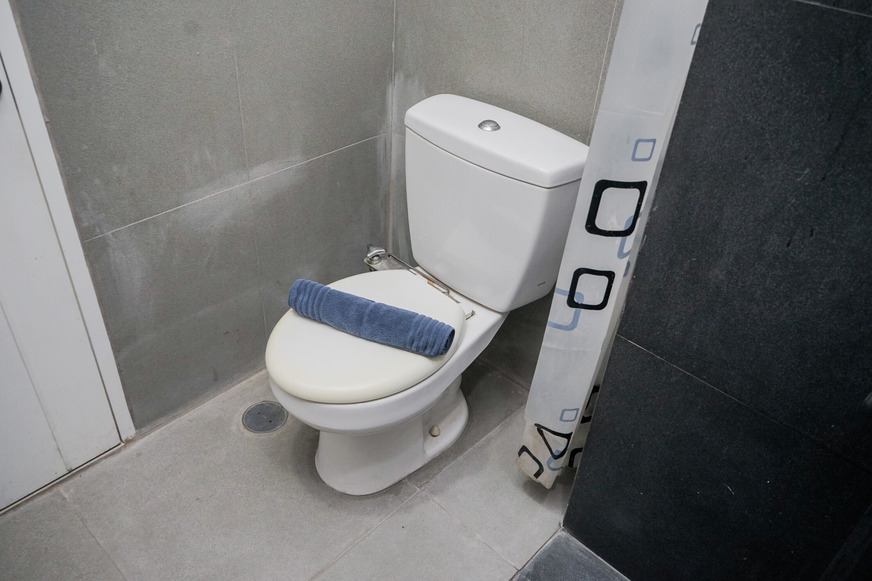A toilet with a towel on the seat, a white door, and a tiled floor.