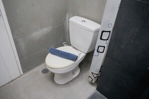 A toilet with a towel on the seat, a white door, and a tiled floor. - Nice and Elegant Studio at Paddington Heights Apartment (Tangerang)