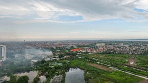A cityscape with a large body of water in the foreground, surrounded by greenery and residential areas. - Delightful Luxurious Studio Room at Taman Melati Surabaya Apartment (Surabaya)