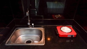 A kitchen with a stainless steel sink and a red induction cooktop. - Delightful Luxurious Studio Room at Taman Melati Surabaya Apartment (Surabaya)