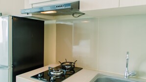 A kitchen with a stove, sink, and cabinets. - Minimalist and Cozy Living Studio Apartment at B Residence (Pagedangan)