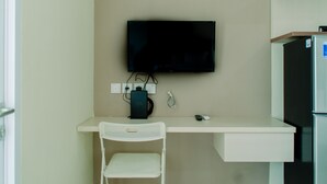A small, white desk with a television mounted above it, a power outlet, and a remote control on the desk. - Minimalist and Cozy Living Studio Apartment at B Residence (Pagedangan)