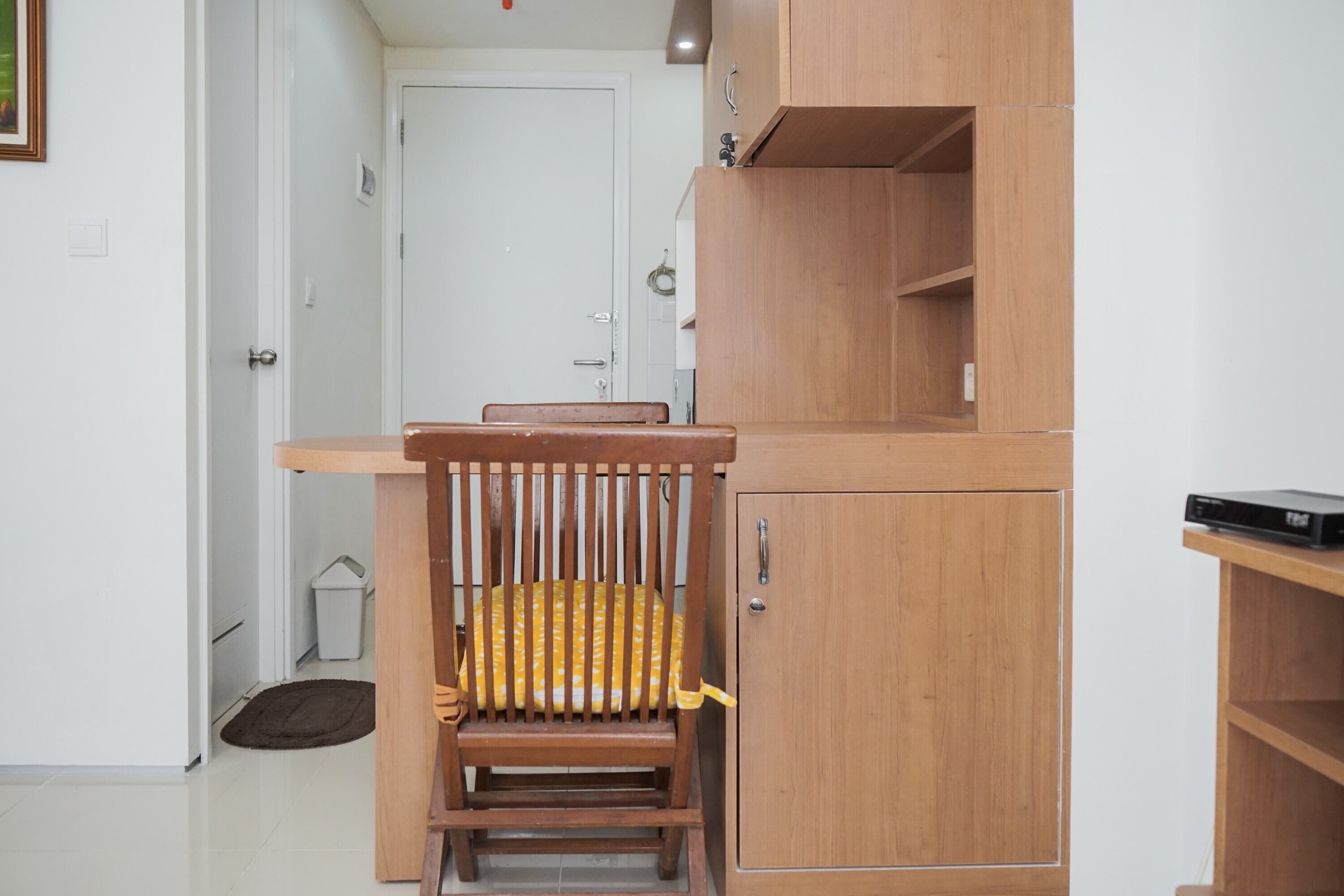 Una habitación pequeña con una silla de madera, un armario y una estantería.