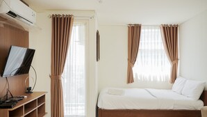 Une chambre à coucher avec un lit, une télévision et une étagère.