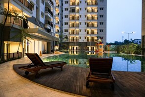 Un espace piscine d’hôtel avec des chaises longues et un élément décoratif aquatique.