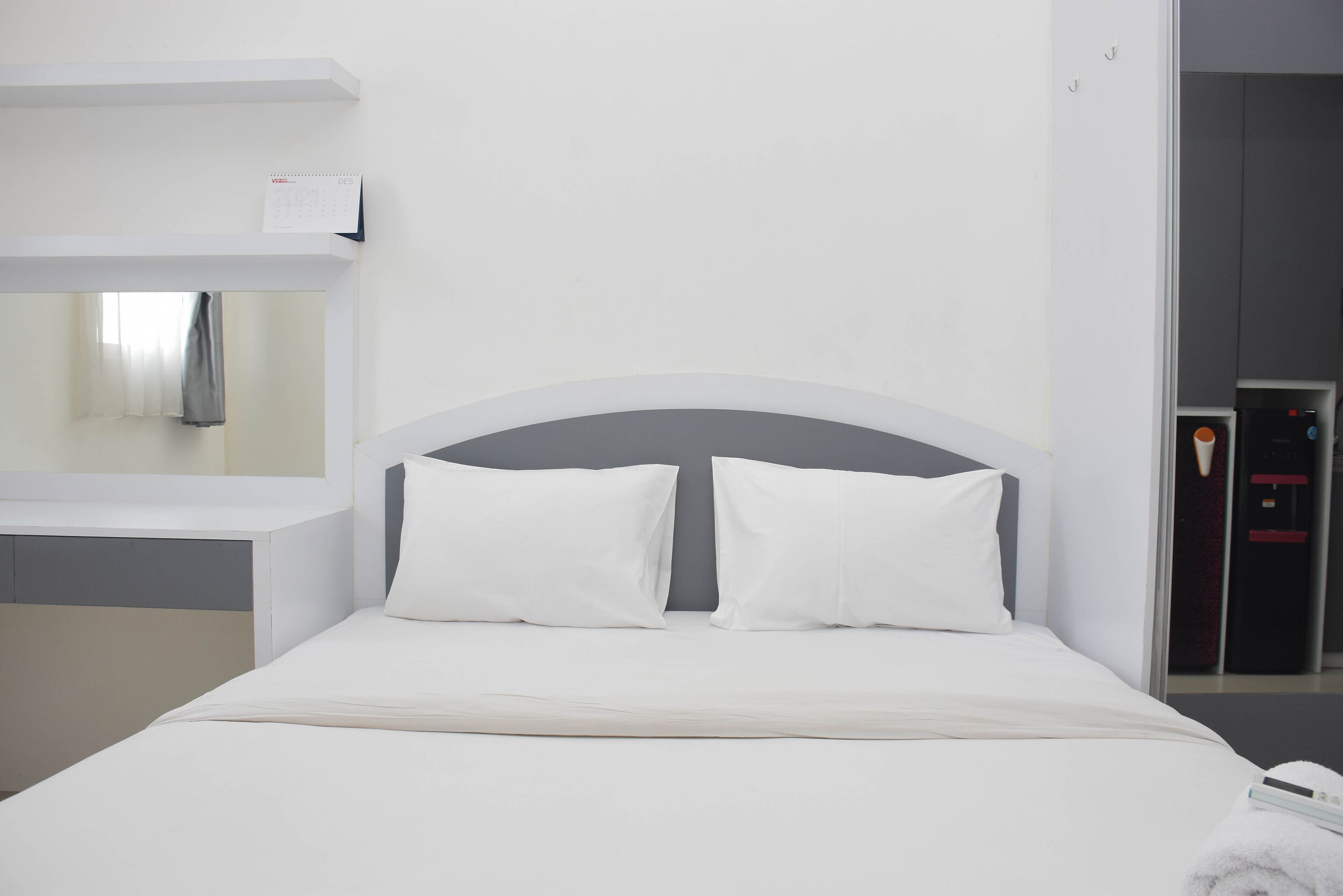 Ein Hotelzimmer mit Bett, Nachttisch, Spiegel und Kleiderschrank.