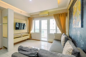 Un salon moderne avec un canapé, un téléviseur et une vue sur le balcon.