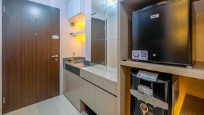 Un baño moderno con puerta de madera, un lavamanos con espejo y un refrigerador GEA.