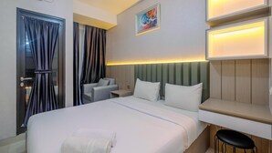 Una habitación de hotel con cama, mesita de noche, silla y escritorio con taburete.