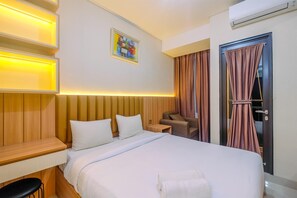 A hotel room with a bed, bedside tables, a chair, a desk, and a painting on the wall. - Homey and Stylish Studio Room at Transpark Cibubur Apartment (Depok)