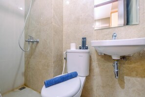 A bathroom with a toilet, a shower, and a sink. - Homey and Stylish Studio Room at Transpark Cibubur Apartment (Depok)