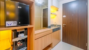 A modern kitchen with a GEA refrigerator, a built-in sink, and wooden cabinets. - Homey and Stylish Studio Room at Transpark Cibubur Apartment (Depok)