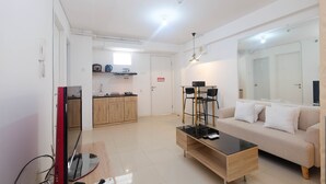 A modern apartment with a kitchen, a living area with a sofa and coffee table, and a dining area with chairs. - Best Choice and Comfy 3BR at Bassura City Apartment (Jakarta)