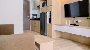 Une cuisine moderne avec des meubles en bois, un réfrigérateur en acier inoxydable, un four à micro-ondes et un téléviseur à écran plat fixé au mur.