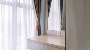 Une pièce avec une coiffeuse en bois, un miroir et des rideaux légers ornés de glands.