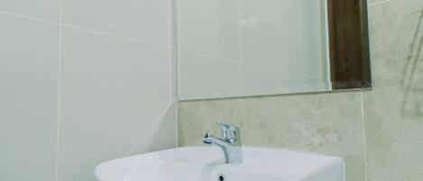 Un baño con lavamanos blanco, espejo y retrete.