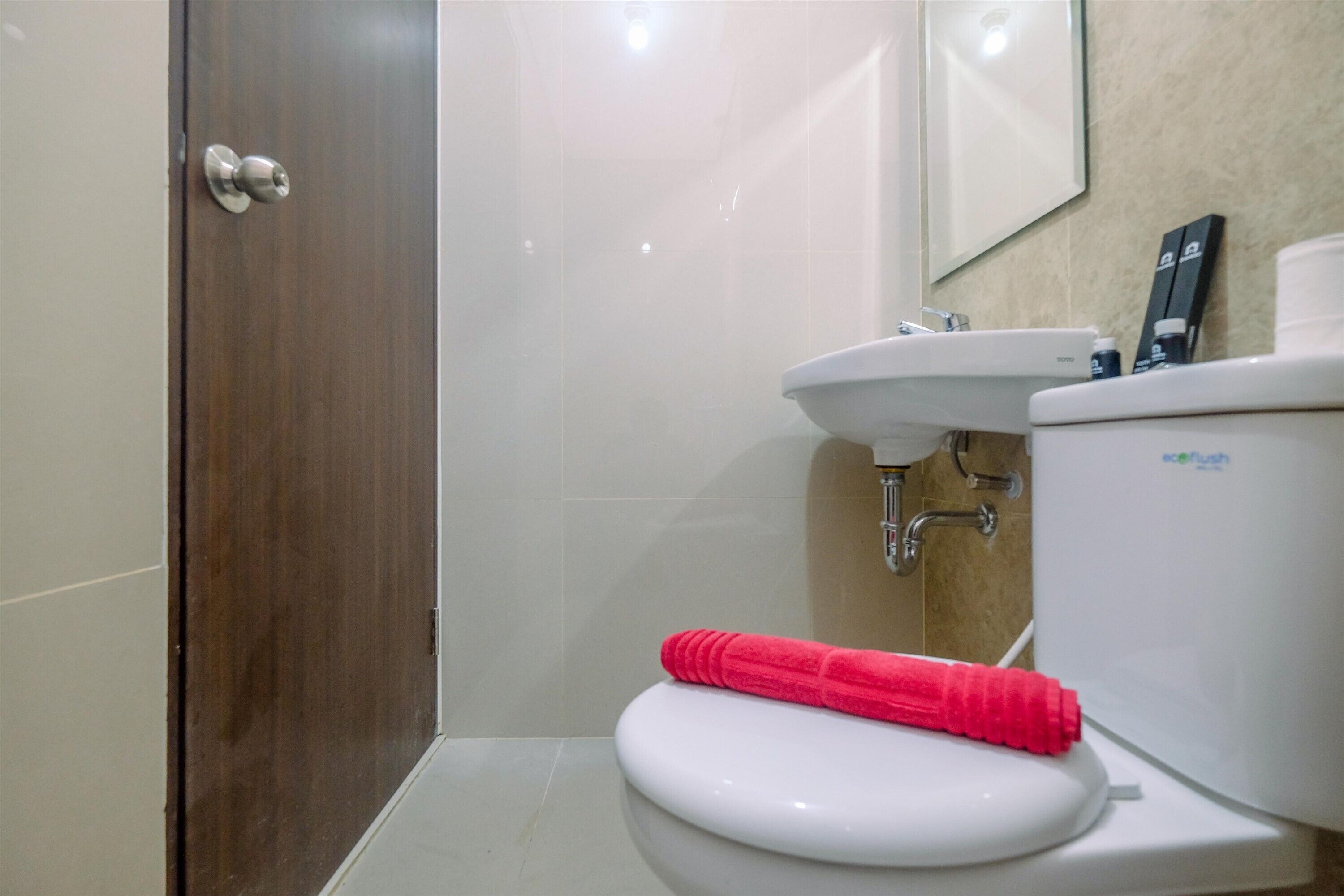 A bathroom with a white toilet, a sink, and a mirror above the sink.