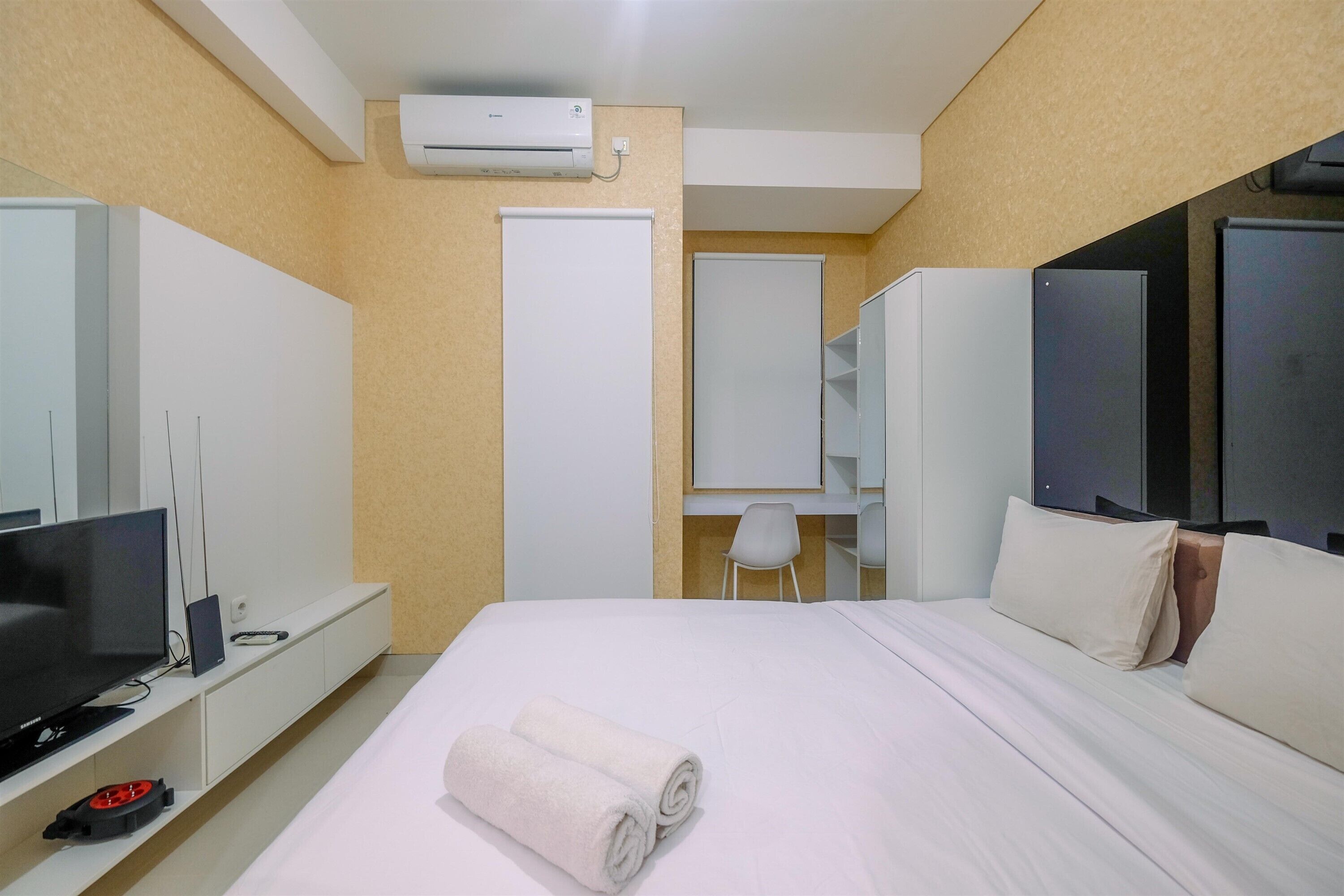 A hotel room with a bed, a TV, a desk, and a chair.