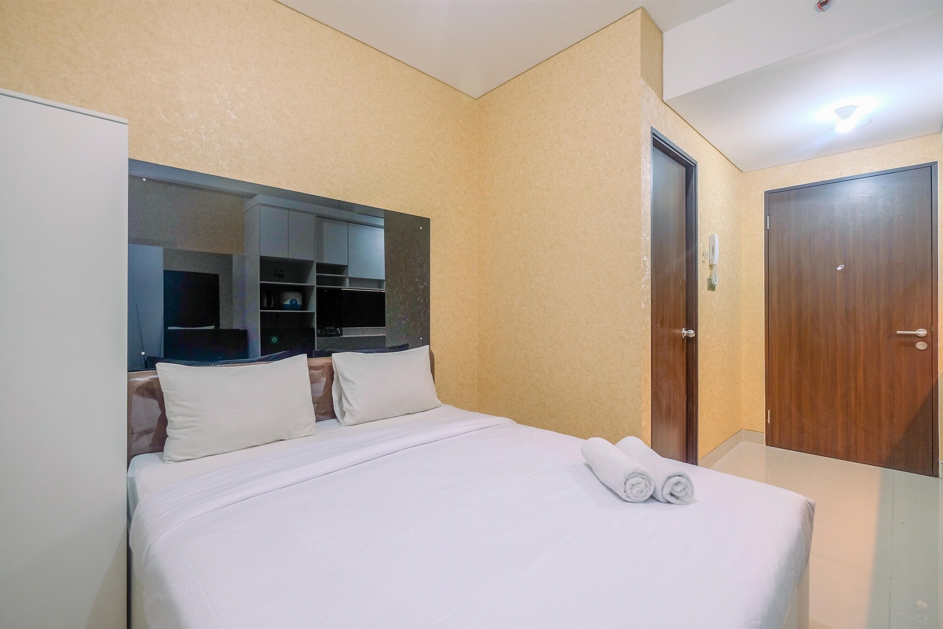 Una habitación de hotel con cama, armario, espejo y puerta.
