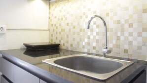 Une cuisine dotée d’un évier en acier inoxydable, d’une balance noire et de carreaux décoratifs sur le mur derrière l’évier.