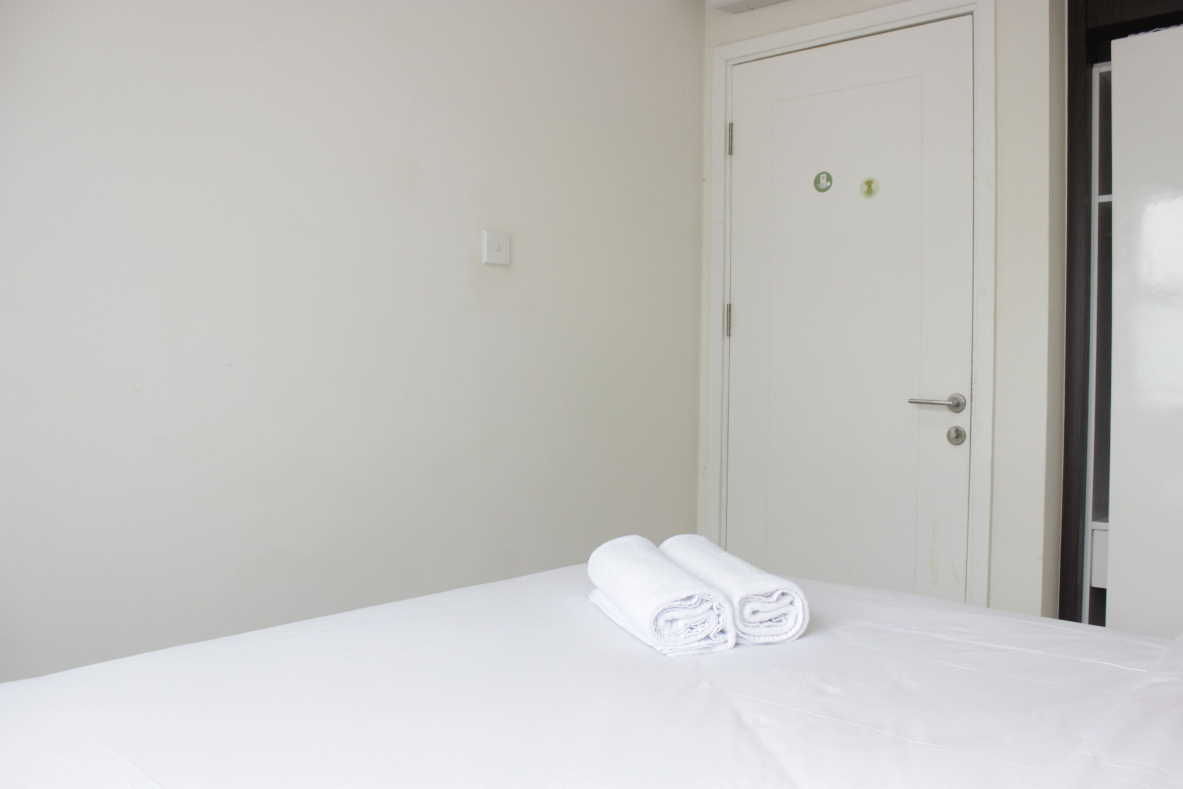 Una habitación de hotel con una cama, una puerta y una toalla sobre la cama.