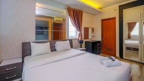 A hotel room with a large bed, a wardrobe, a mirror, and a window with curtains. - Posh 3BR Residence at Grand Palace Kemayoran (Jakarta)